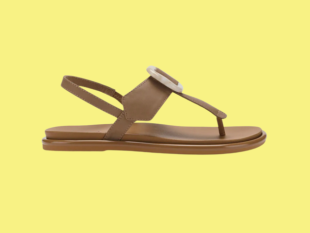 A pair of tan sandals with a T strap and buckle against a white background.
