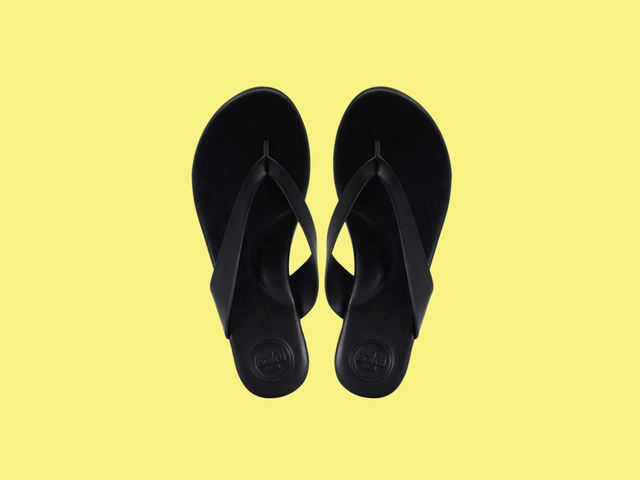 A pair of black flip flops against a white background.