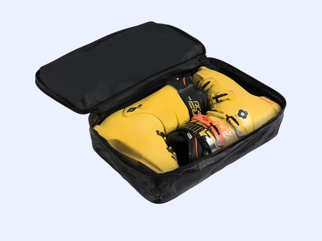 Two yellow ski boots inside a black cube against a light blue background