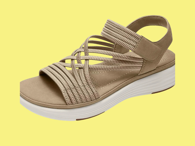 A strappy beige and white sandal against a white background.