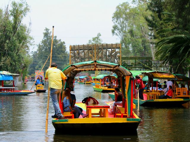 A canal-like river with colorful boats in it in Xochimilco.
