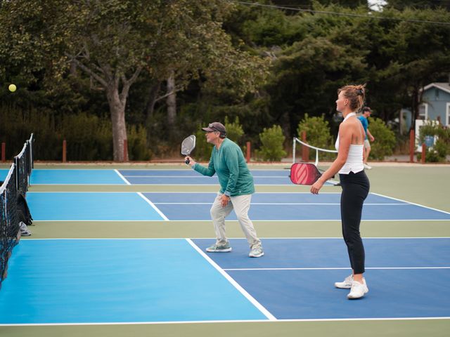 Two players on a blue pickleball court in the middle of a match.