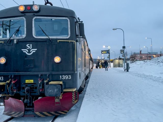 An SJ night train parked in a snowy train station.