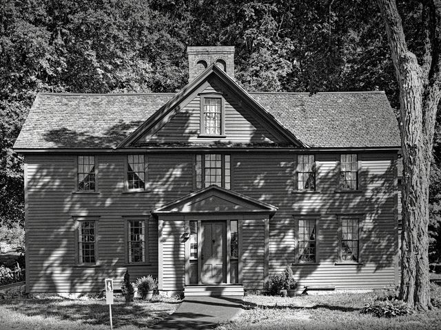 The historic home of Louisa May Alcott with wood siding is photographed in black and white.