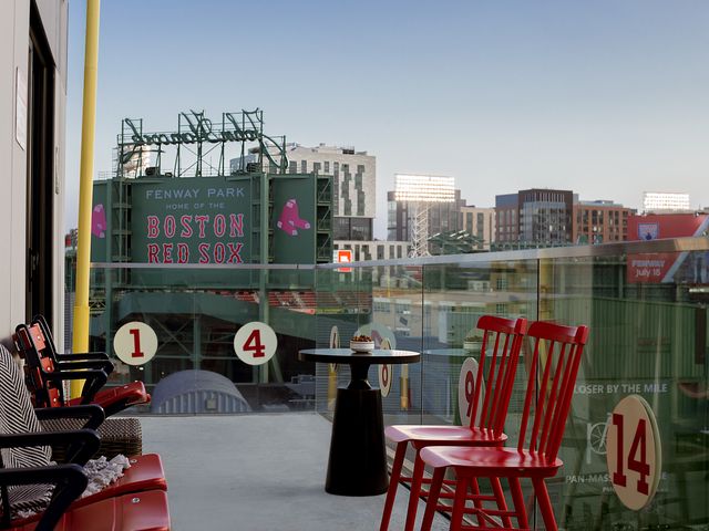 A balcony with red seats and numbers next door to the exterior of Fenway Park in Boston.
