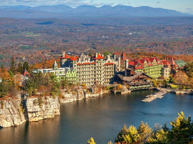 The Mohonk Mountain House overlooking a river and cliffs surrounded by autumnal foliage.