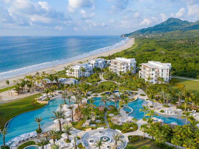 An aerial view over Conrad Punta de Mita, a tropical resort with lagoon-style pools facing a pretty beach.