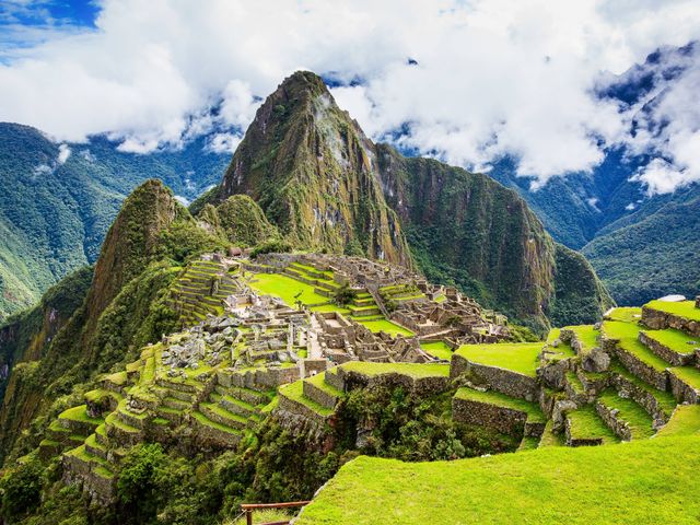 An aerial view of Macchu Picchu in Peru with mountains and clouds.