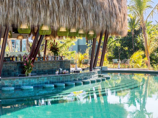 A pool bar with stools in the water and a thatched roof at Club Med Michès Playa Esmeralda.