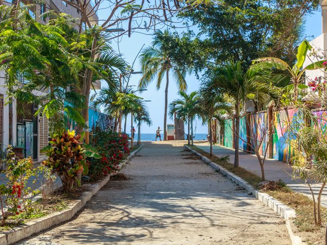A small street with painted buildings leads to a beach.