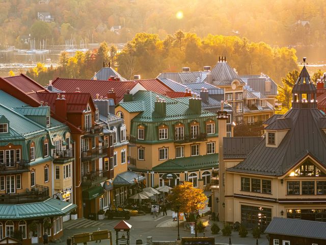  A view over Mont-Tremblant in Quebec, Canada with house roofs in golden sunlight surrounded by autumnal maple trees.
