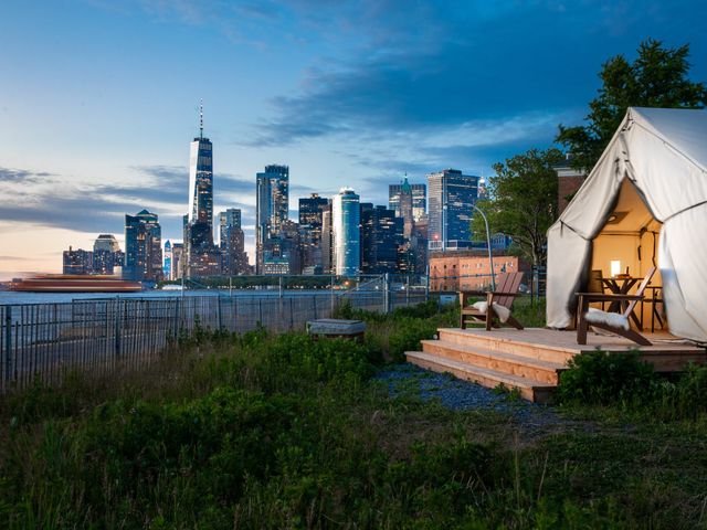 A view of the New York City skyline as seen from a tent facing it with the river in between.