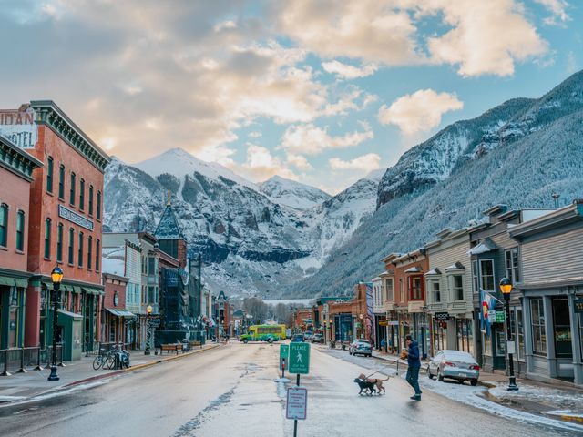 A charming street in Telluride with shops on either side of the road and mountains in the distance behind it.