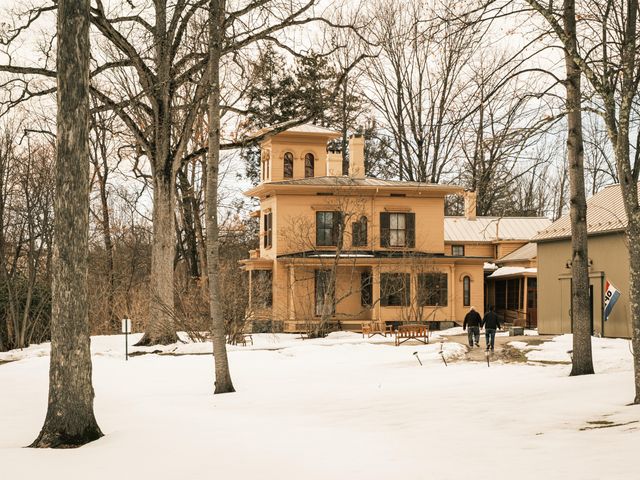 A yellow Victorian-style home in a snow-covered area with bare trees.