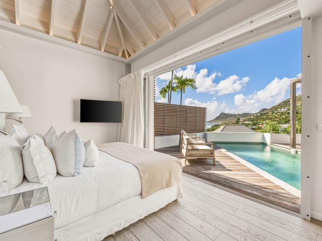 A hotel room at Le Toiny St. Barth with a bed facing a deck with a private pool.
