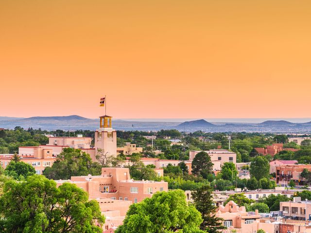 An aerial view over the Sante Fe treetops and skyline at sunset.