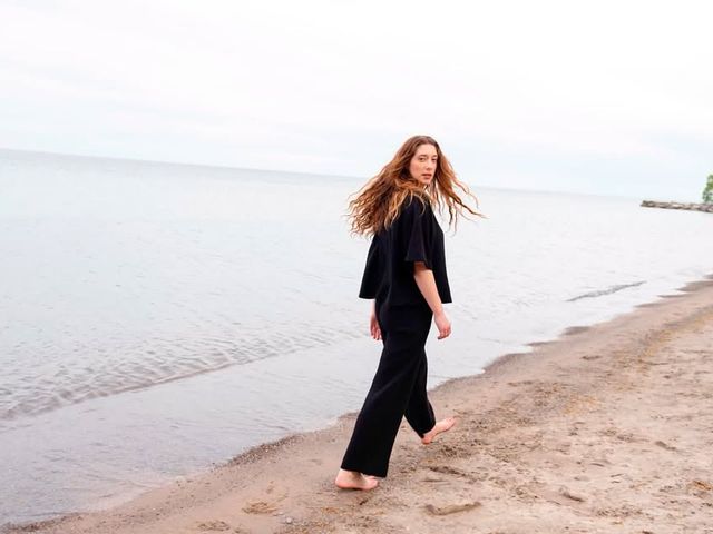 A woman walks on the beach in a matching black outfit set.