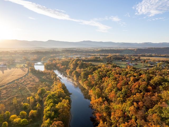 The Shenandoah River is seen from an aerial view during fall with autumn foliage all around.