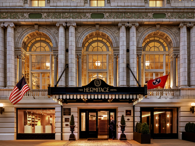 The exterior of The Hermitage Hotel with grand windows, flags, and a stately entrance.