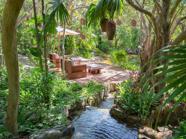 A peaceful deck with seating surrounded by lush trees, jungle foliage, and bodies of water.