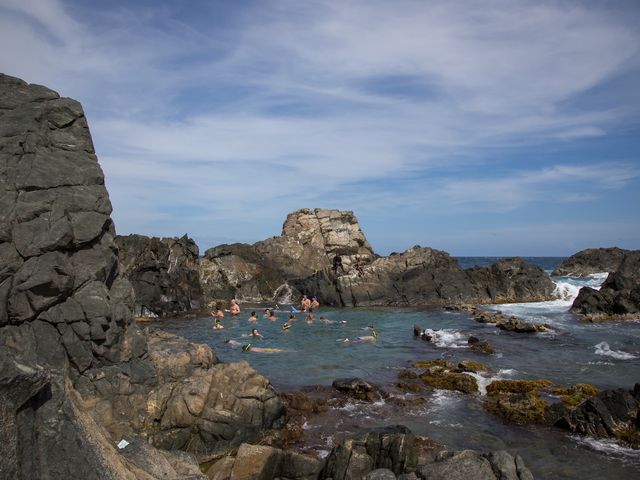 A group of swimmers in a natural ocean pool surrounded by rocks.
