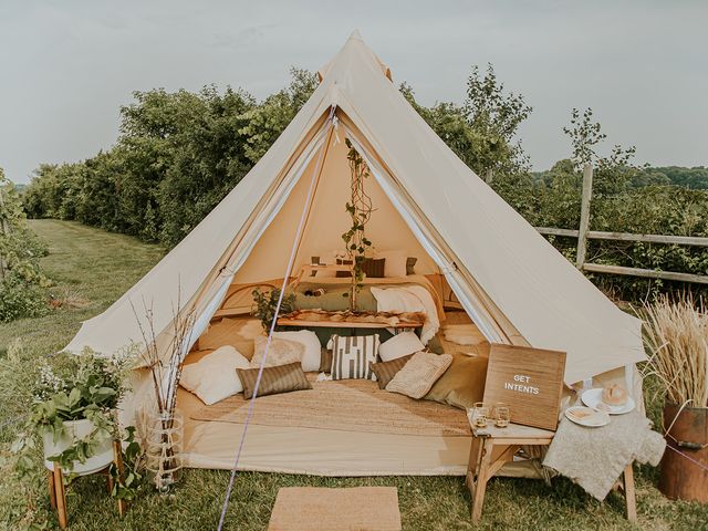 A glamping tent at Wild Mountain Winery with the front open to review a bed and pillows for seating next to a winery.