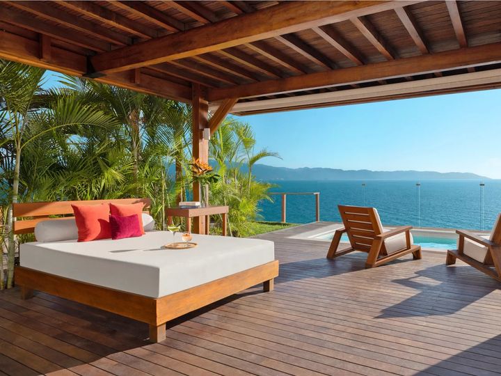 A sunbed, lounge chairs, and infinity pool looking out at the ocean at Dreams Vallarta Bay Resort & Spa.