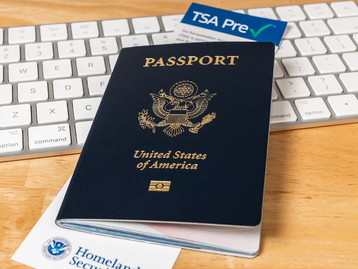 United States of America Passport with Department of Homeland Security TSA Pre Check registration information card. US Passport on desk with computer keyboard.
