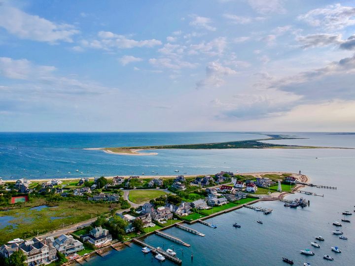 An aerial view over a portion of the island of Nantucket with waterfront homes and docks.