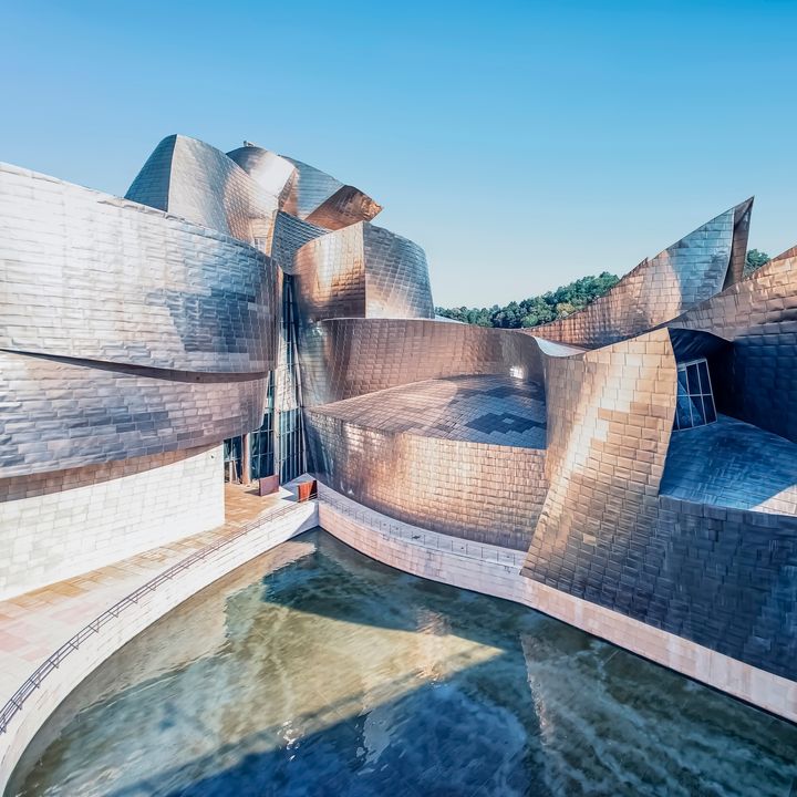 The futuristic looking exterior of the Guggenheim in Bilbao, Spain with its silver and titanium edges.
