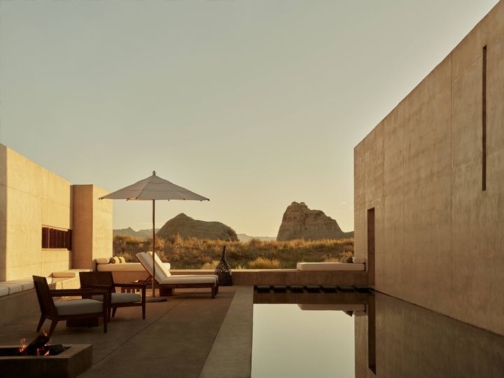 An outdoor terrace with a private pool overlooks sweeping desert scenery bathed in the golden light of sunset.