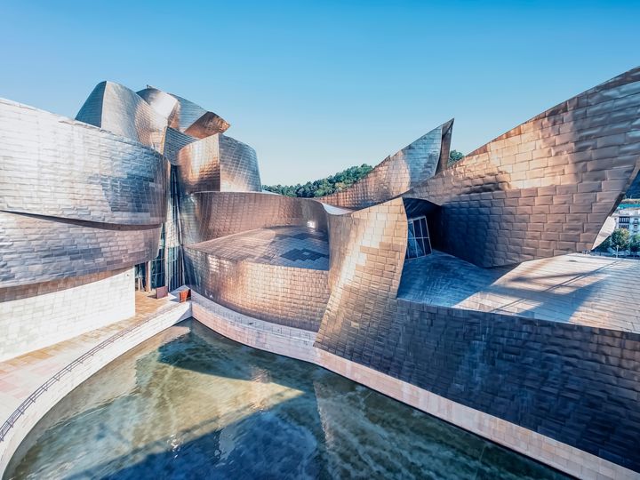 The futuristic looking exterior of the Guggenheim in Bilbao, Spain with its silver and titanium edges.
