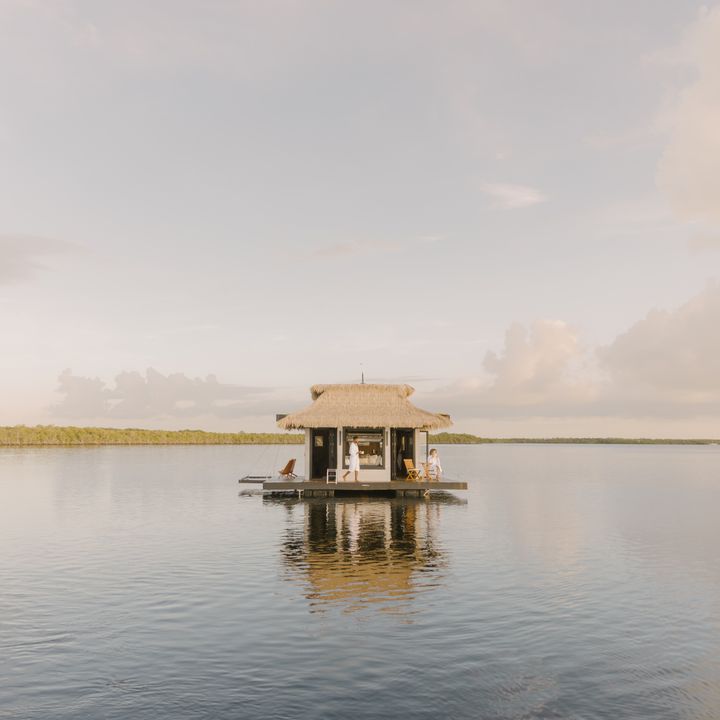 A floating thatched-roof bungalow floating on top of the water in the Florida Keys.