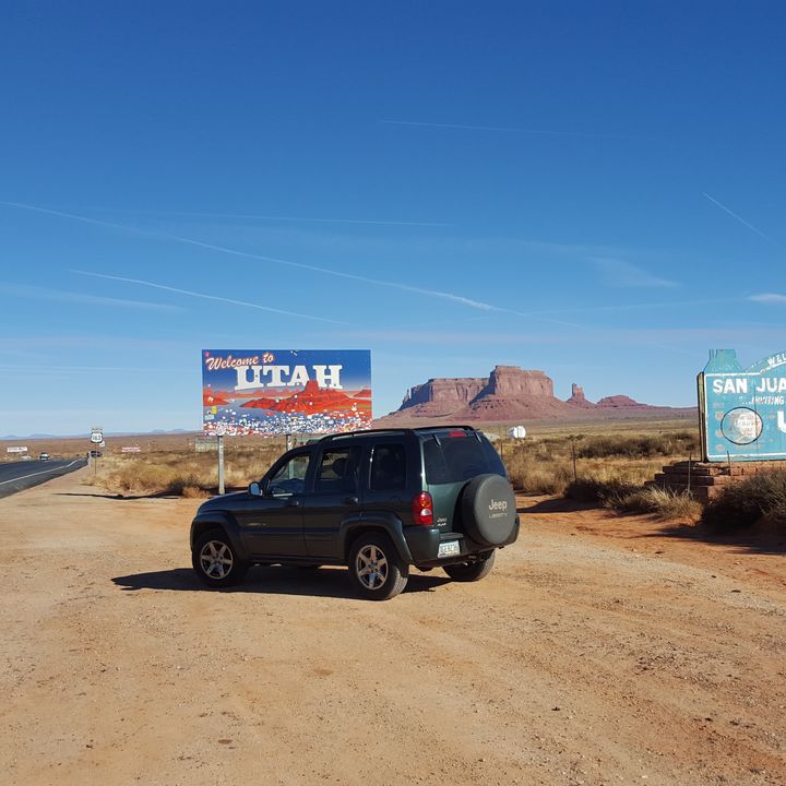 A car on the side of the road next to a welcome to utah sign.