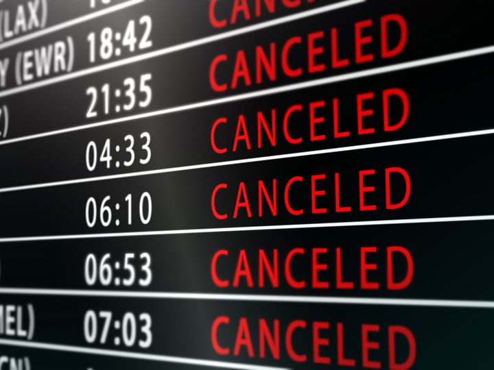 A flight status board in an airport lists rows of departures as ‘canceled’ in red.