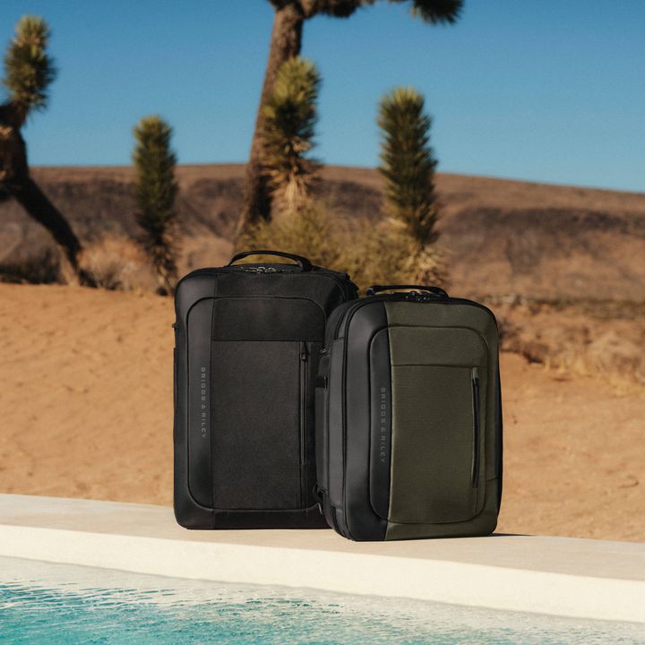 Two backpacks sit on the edge of a pool in the desert.