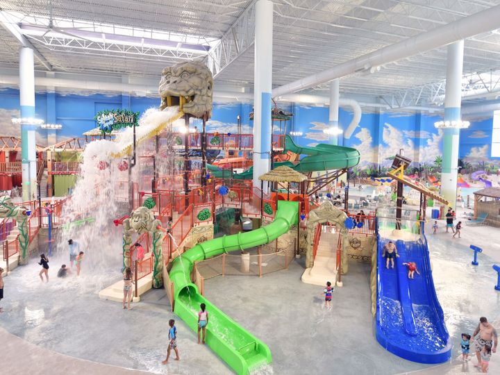 An elaborate indoor water park with a play structure, water slides, and interactive water features at Kalahari Resort Round Rock.