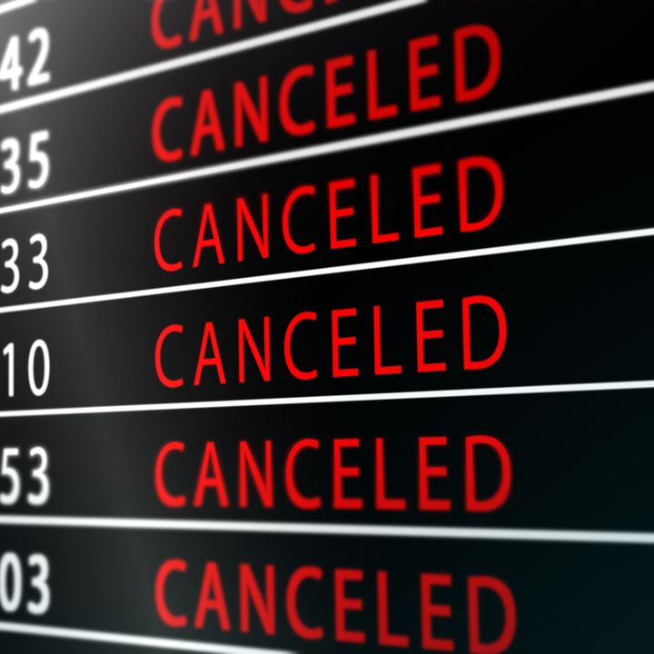 A flight status board in an airport lists rows of departures as ‘canceled’ in red.