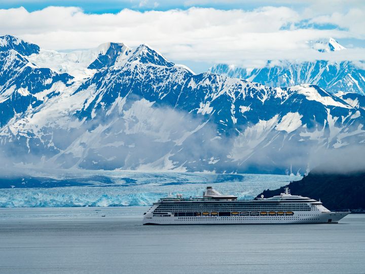 A cruise ship in Alaska passing glaciers and snow-capped mountains.