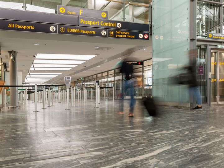 A passport control line area in an airport with a blurred-out tourist going through.