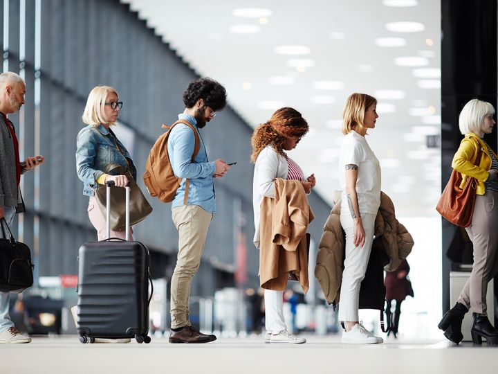 Travelers waiting in line with luggage at an airport