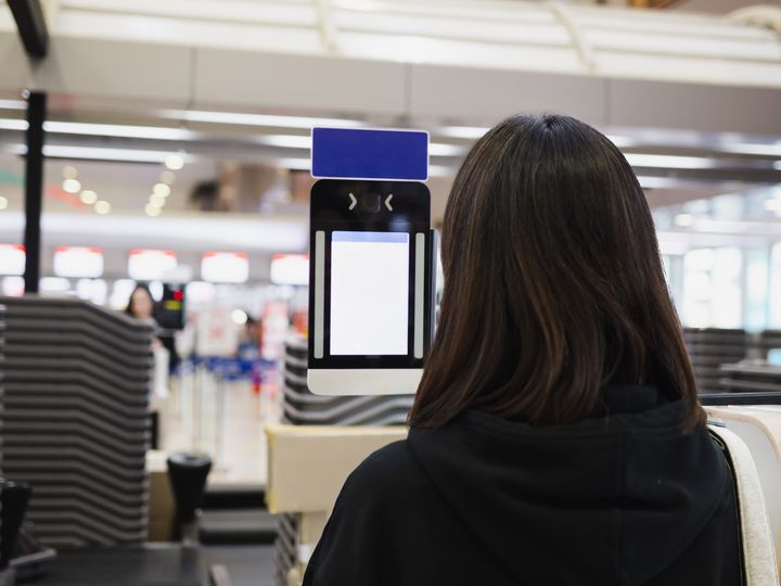 A woman is seen using a facial scanner at the airport with only the back of her head visible.
