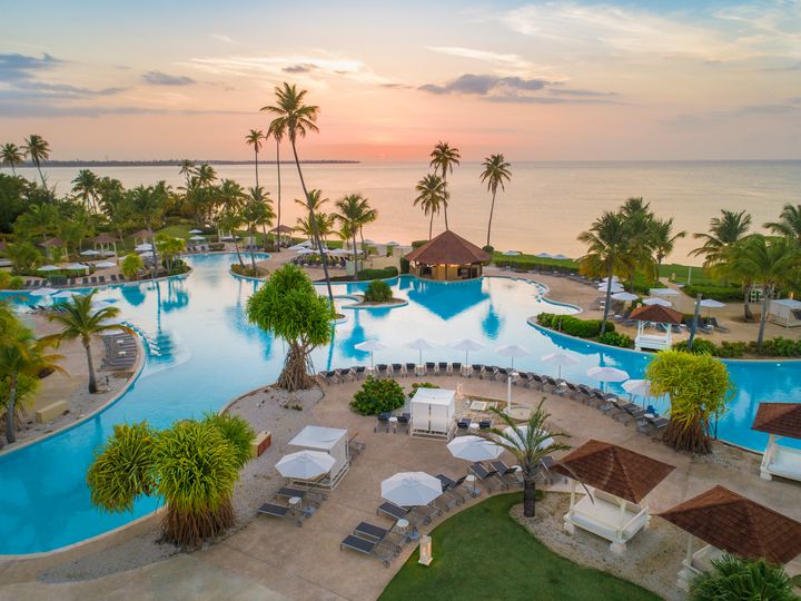A sprawling lagoon-style pool next to the beach at sunset at the Hyatt Regency Grand Reserve Puerto Rico
