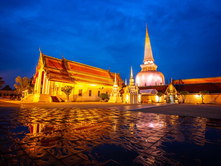 The monastery buildings of Wat Phra Mahathat Woramahawihan with cloudy sky at night at Nakhon Si Thammarat in Thailand.
