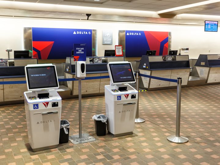 An empty Delta check-in area with kiosks and terminals to check luggage.