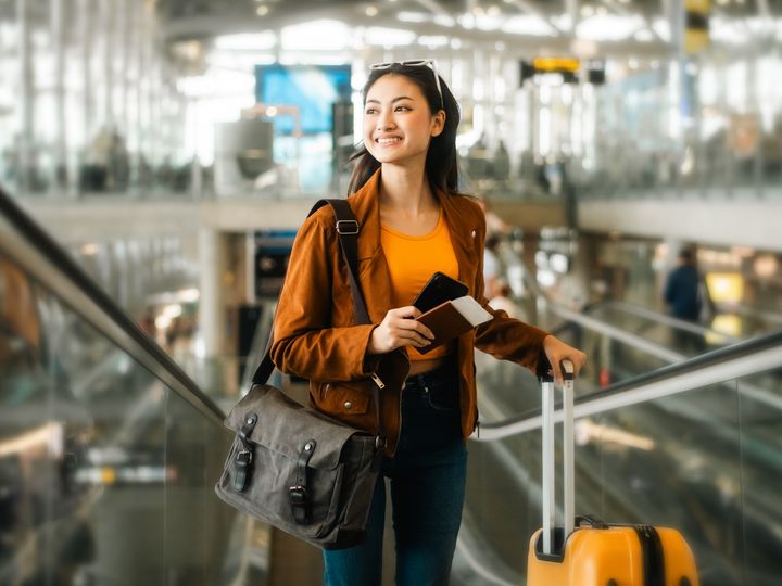 Smiling young woman holding passport in the airport