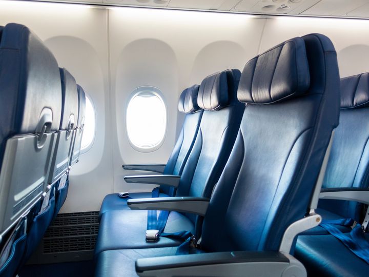 Rows of empty blue airplane seats facing the window.