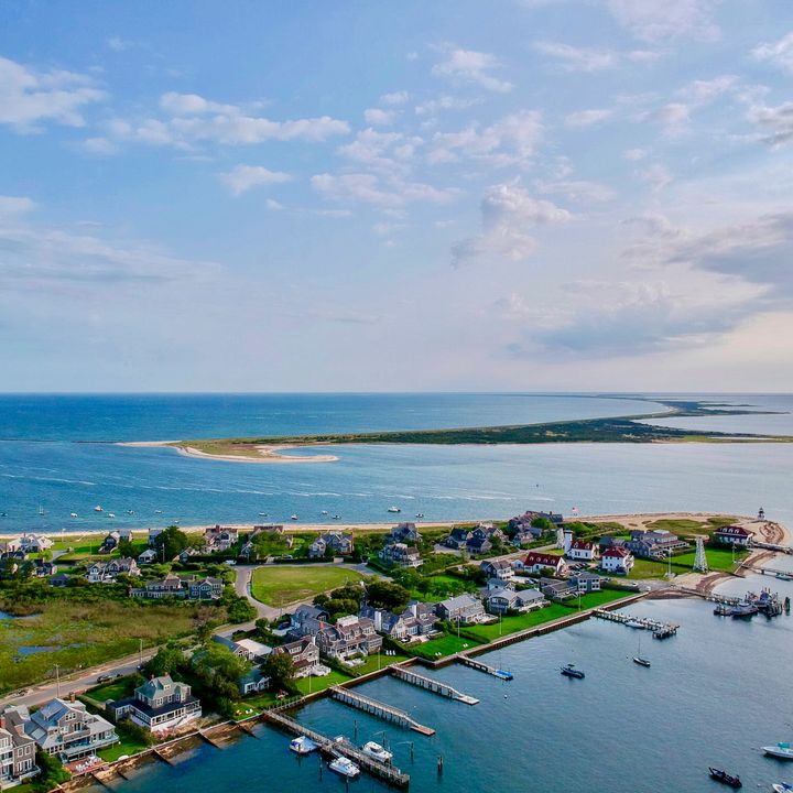An aerial view over a portion of the island of Nantucket with waterfront homes and docks.