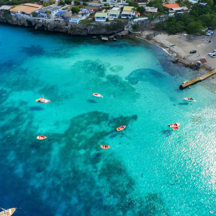 An aerial view over Westpunt in Curacao with its turquoise, blue clear waters alongside a small shore area,.
