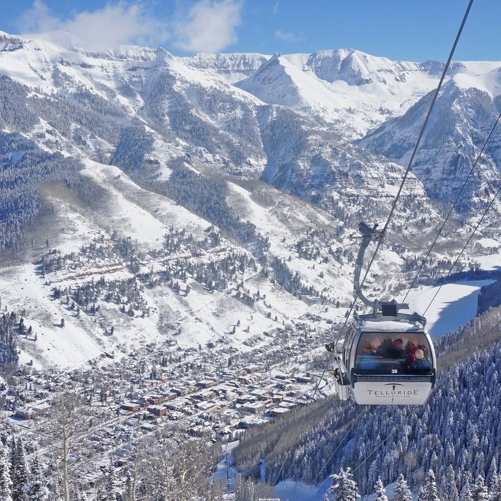 A gondola in Telluride photographed in front of a snow-covered mountain.